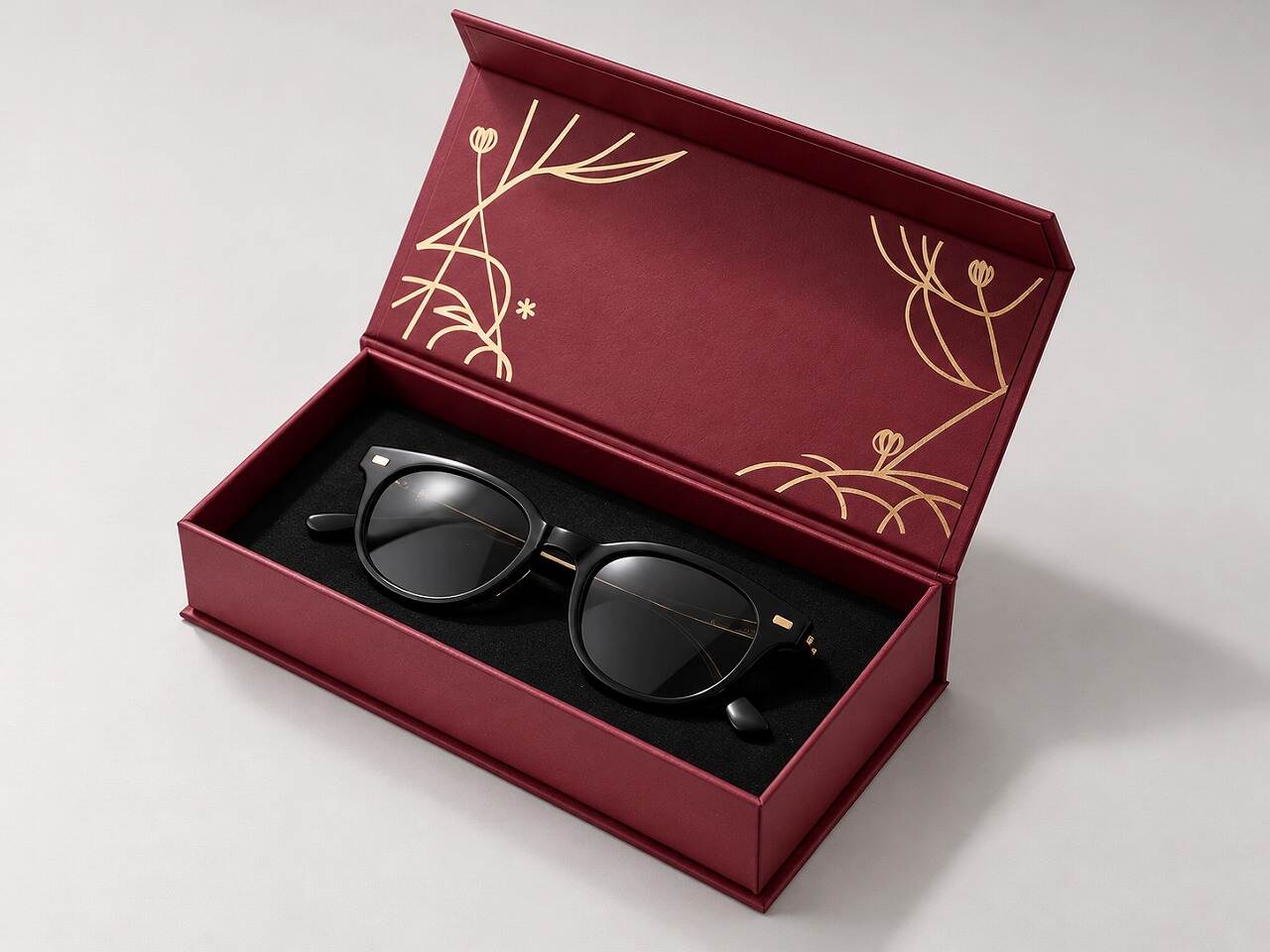 Open burgundy custom rigid paper eyeglasses case box with one pair of glasses in a fitted black insert Open burgundy custom rigid paper eyeglasses case box with one pair of glasses in a fitted black insert